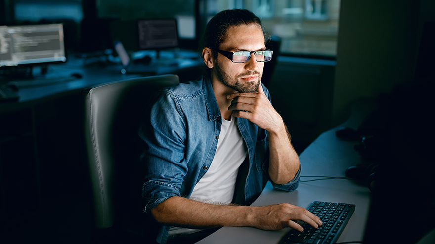 white beared male in glasses stares at computer screen